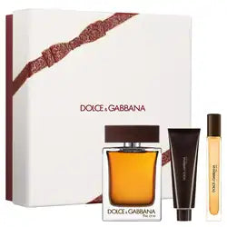 Dolce & Gabbana The One fragrance gift set featuring a large white box with a brown ribbon, a rectangular glass perfume bottle with amber liquid and dark brown cap, a dark brown tube, and a small sample vial with amber liquid, all on a white background.
