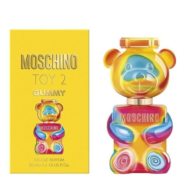 Moschino Toy 2 Gummy Eau de Parfum bottle and packaging box. The bottle is shaped like a colorful gummy bear with a yellow, blue, pink, and orange gradient, and the box is bright yellow with gold lettering.